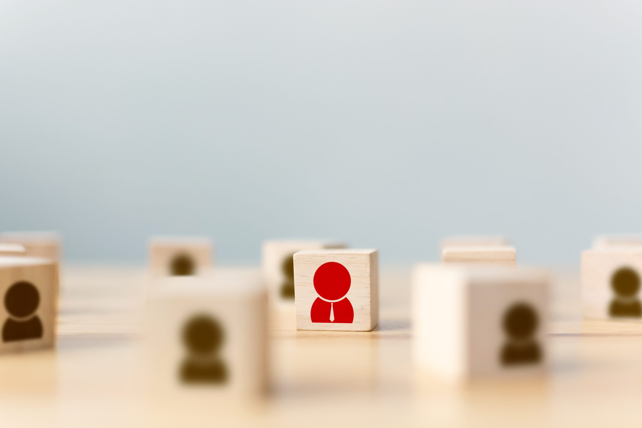 Hand of a businessman chooses a wooden cube block with icon people standing out from the crowd. Successful business team leader concept