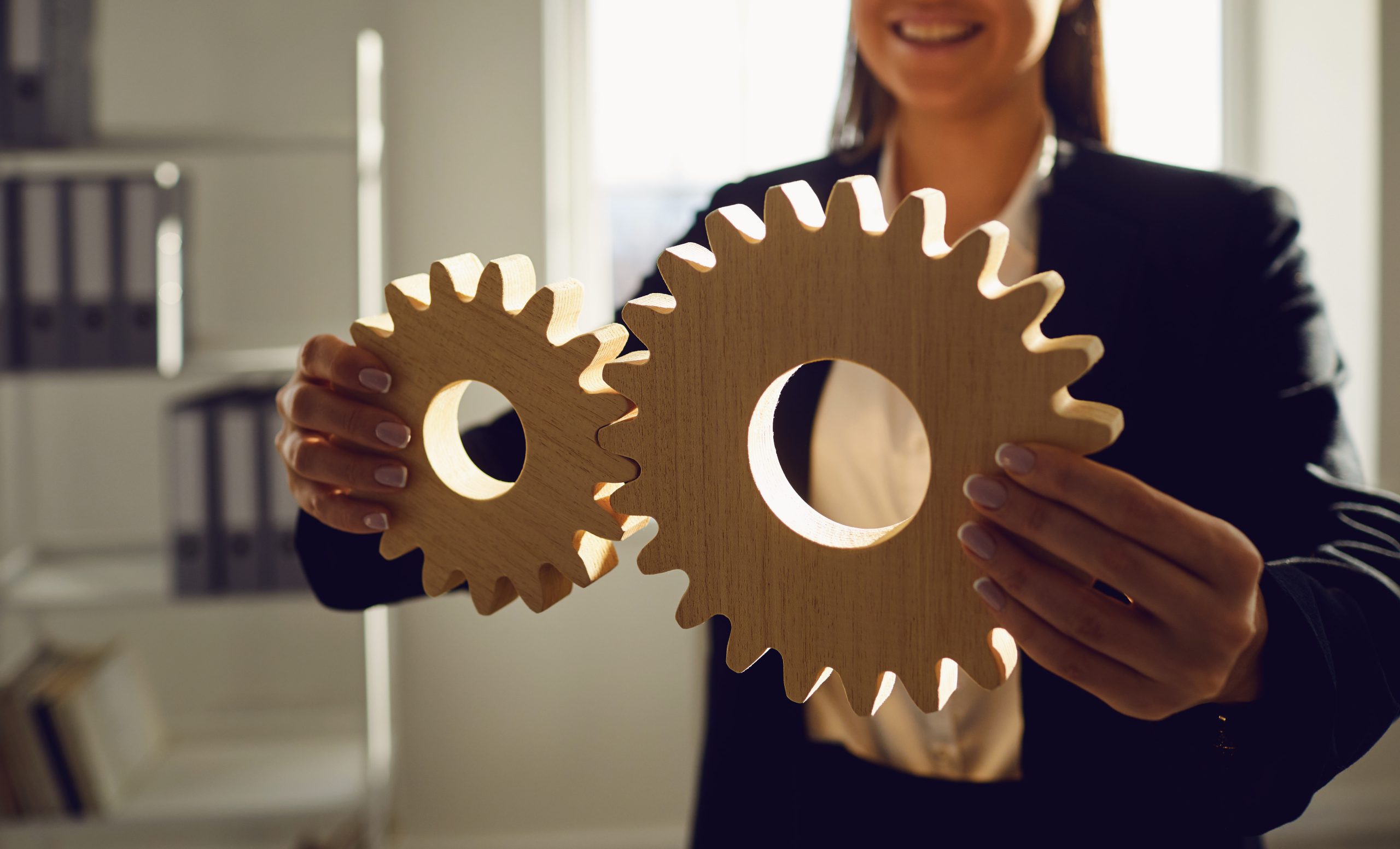Faceless Businesswoman holding wooden gears in his hands in the office with windows